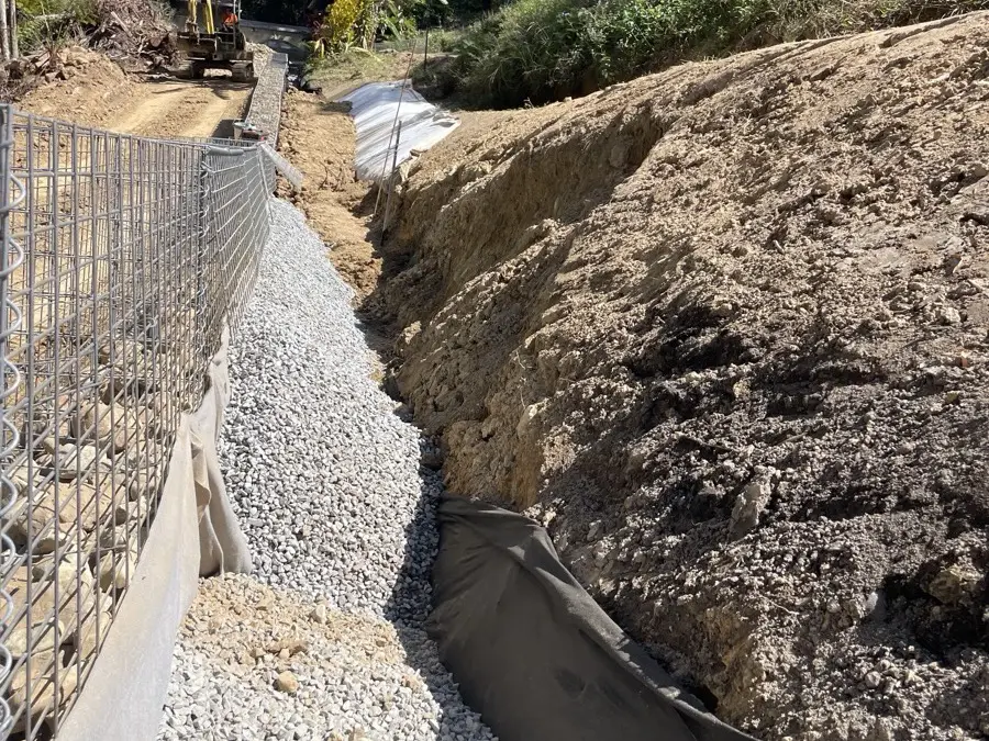 Drainage aggregate and geotextile backfilled behind a new gabion retaining wall